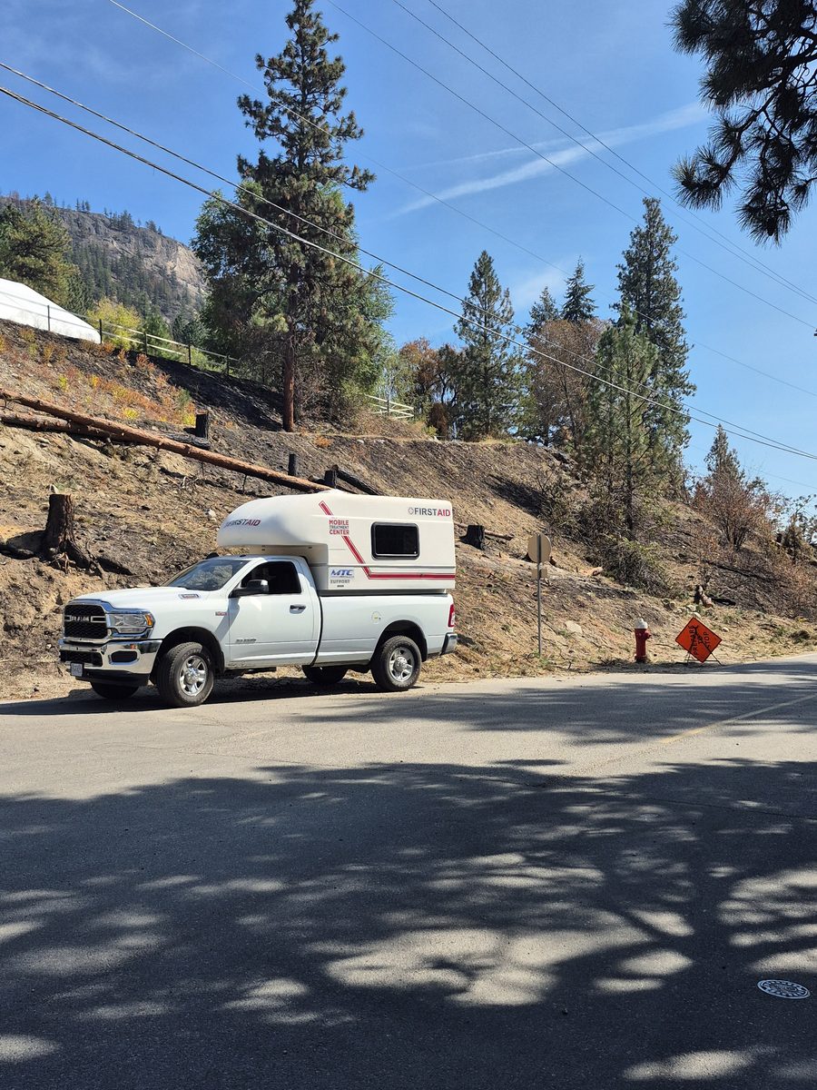 Vital Safety Mobile Treatment Centre parked on a closed road below a fire-scorched hillside in Summerland, BC